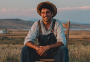 u3139919916_picture_of_a_young_farmer_smiling_sitting_on_a_ch_80f7e72a-7859-45b2-a019-61dd3a682567_0